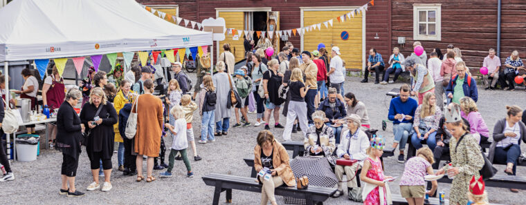 Bild på ett folkhav. Tillvänster köar folk framför ett mattält. Till höger sitter folk på bänkar, äter och umgås.
